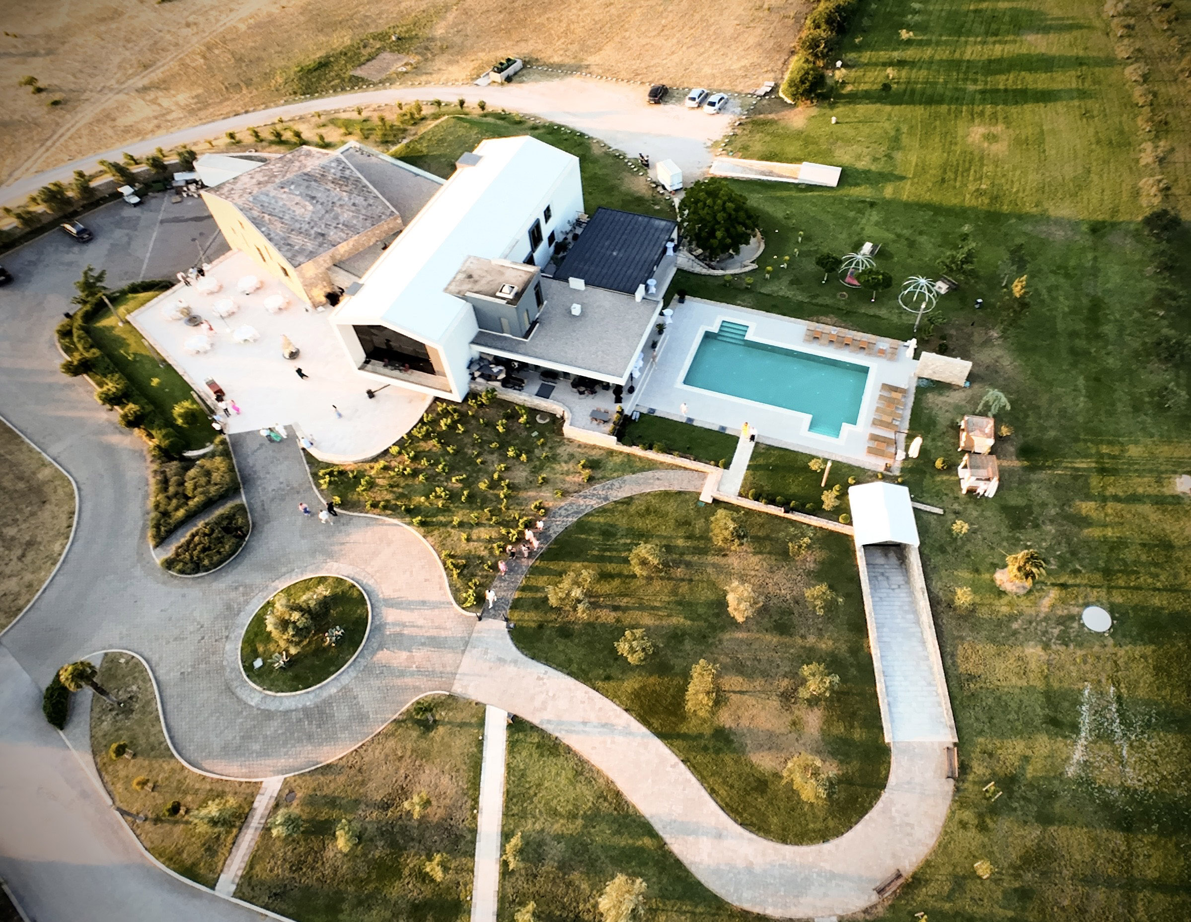 birdseye view of a luxury hotel with a pool, main modern building, driveway, roundabout