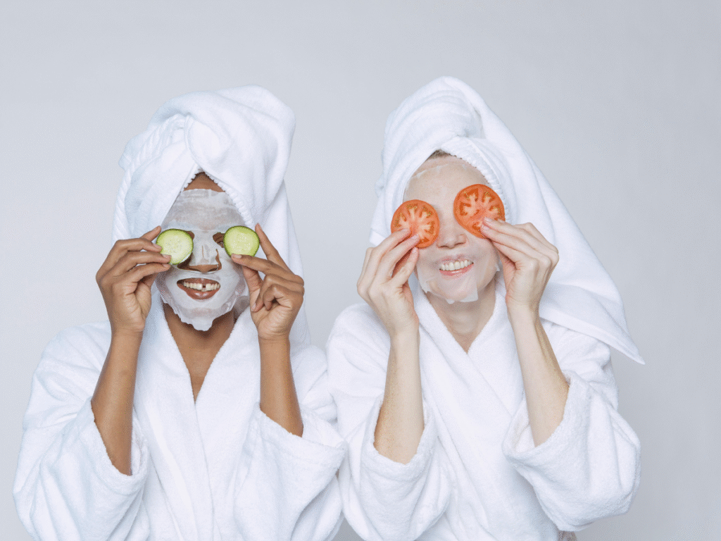 Two women wearing bath robes wearing sheet masks