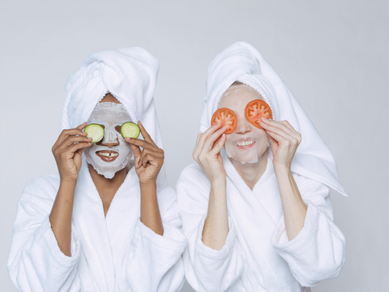 Two women wearing bath robes wearing sheet masks
