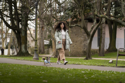 Woman in long coat walking in a park with her dog