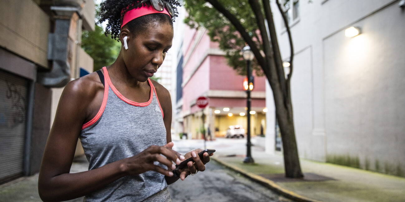 A woman checks her phone while out for a run.