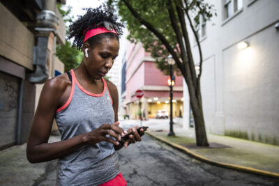 A woman checks her phone while out for a run.