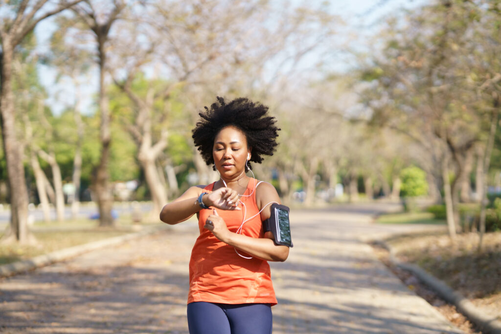 A woman running in the park while checking her watch