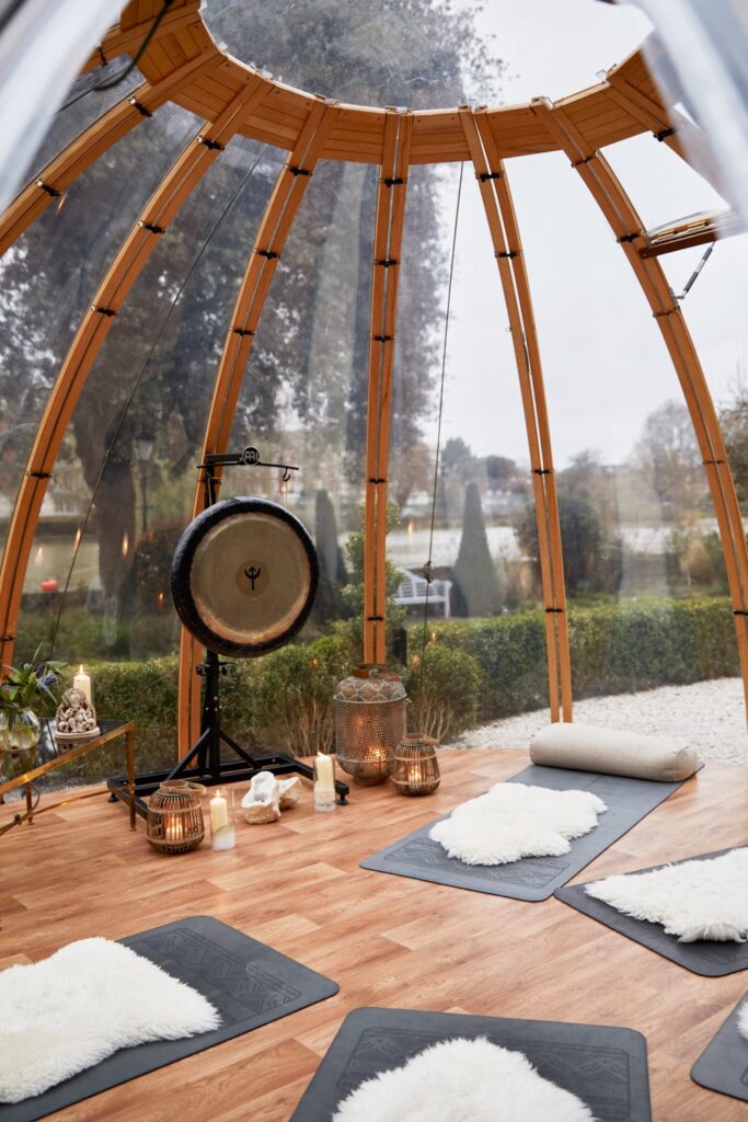 Outward view from inside the dome at bhuti where yoga mats are on the floor as well as gong, lantern lines 
