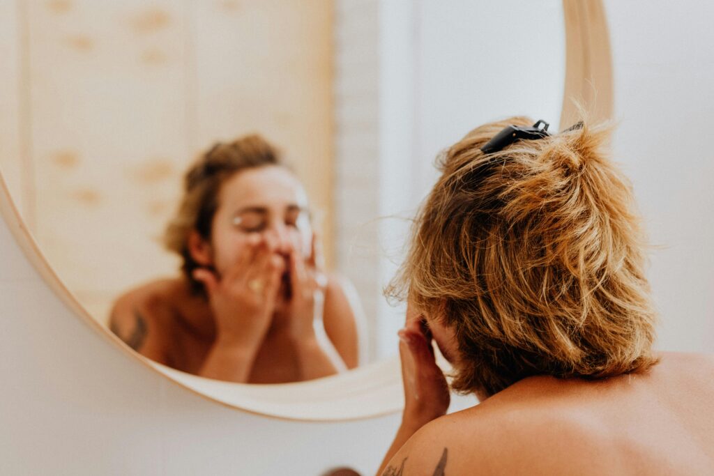 Woman washing her face in mirror