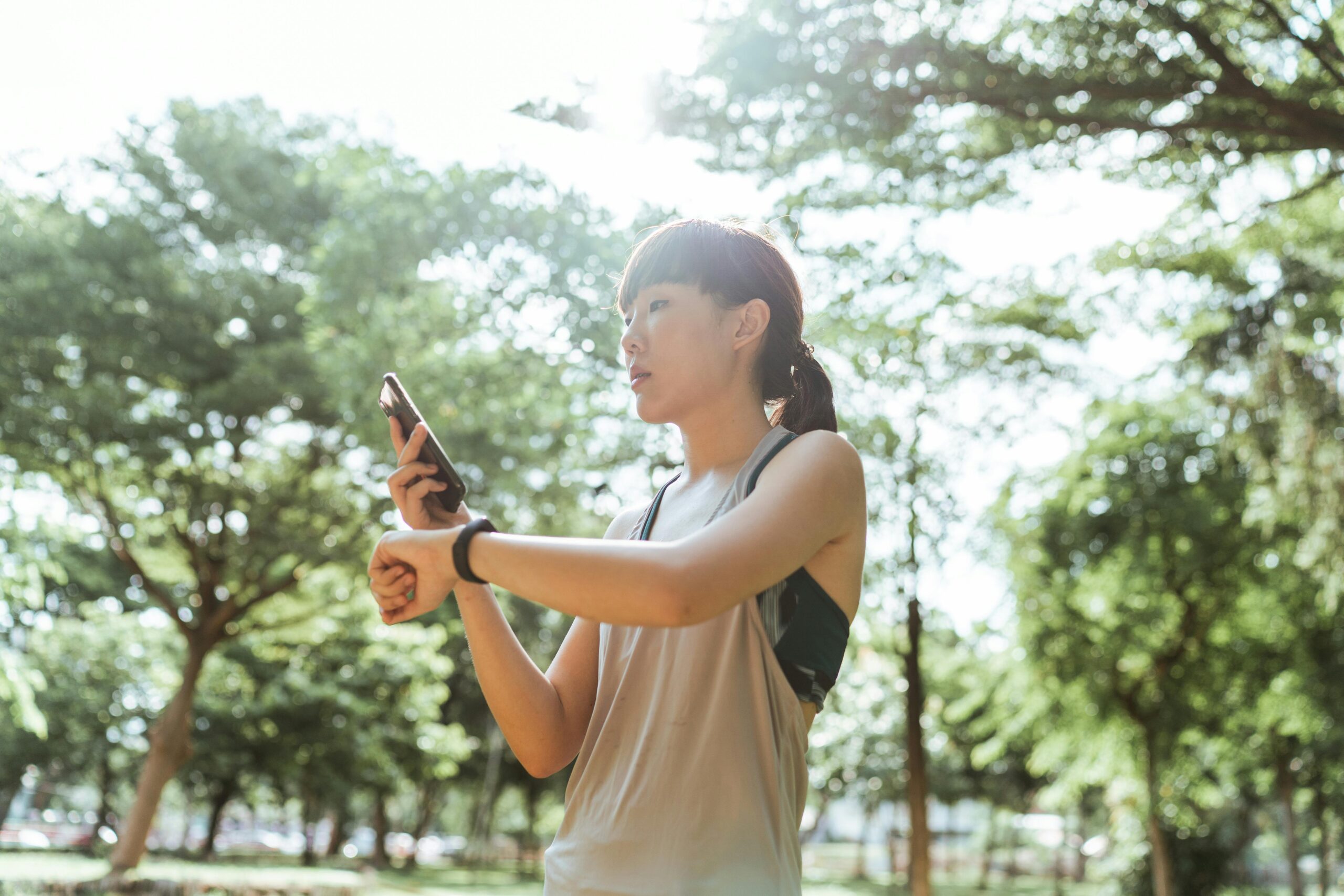 woman in park in workout clothes looking at her smartphone for interval walking