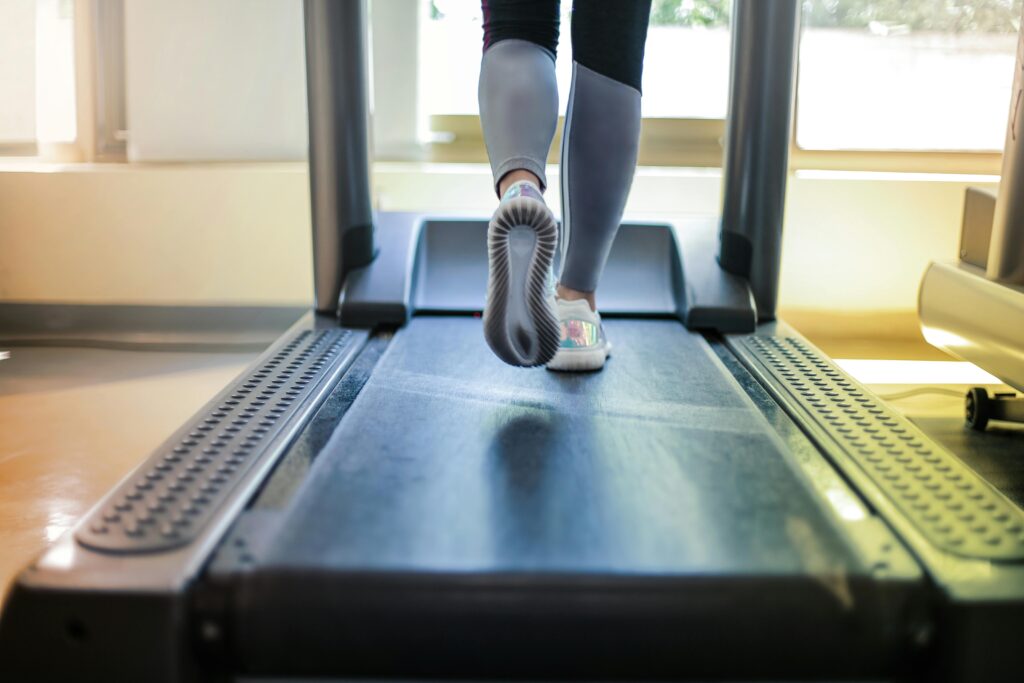 Lower half of a woman's legs and trainers walking on a treadmill