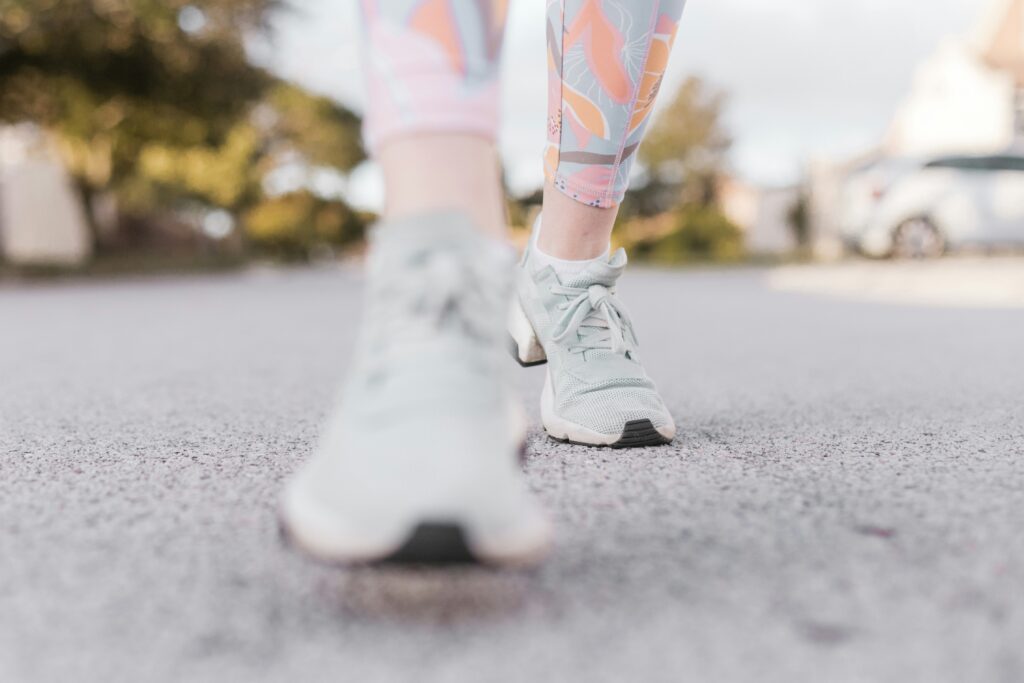 bottom of woman's legs in workout leggings and trainings walking on pavement