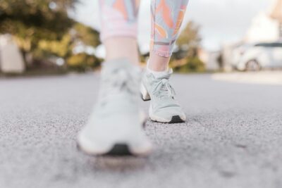 bottom of woman's legs in workout leggings and trainings walking on pavement