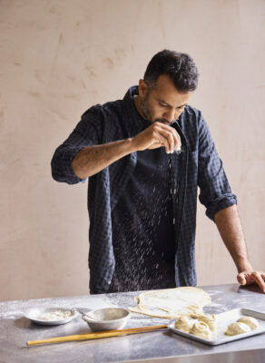 Karan Gokani male chef sprinkling flour while making round flatbreads