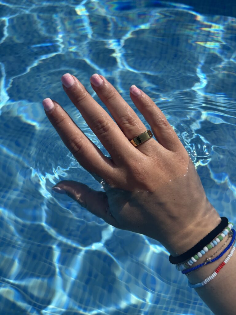 Evelyn's hand wearing RingConn 2 in a pool