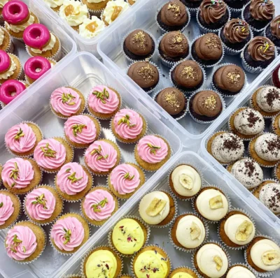 Plastic boxes of cupcakes with coloured icing 