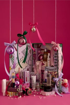 Anthropologie’s 24 Days of Beauty Advent Calendar baubles hanging down with ribbon on fuchsia background