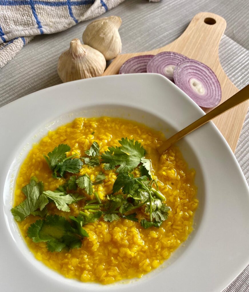 A bowl of bright yellow tadka dhal. 