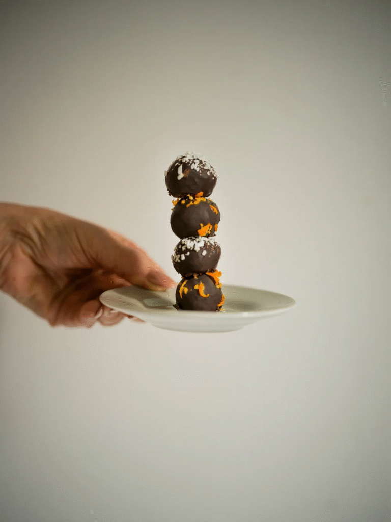 A stack of four orange and coconut energy balls.