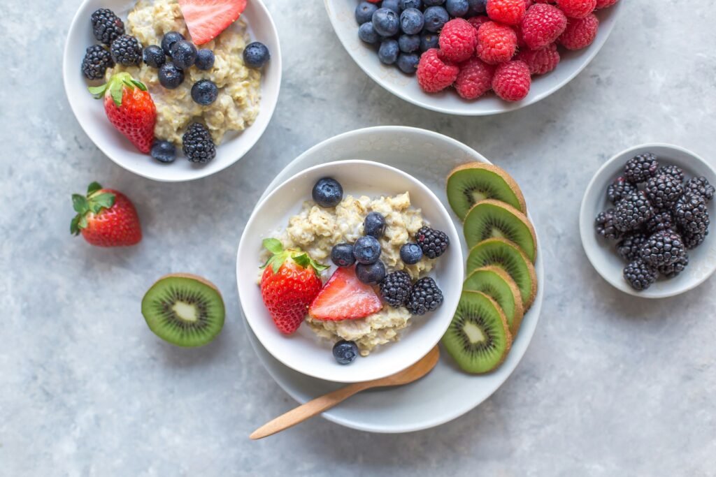 A bowl of porridge topped with fruits including strawberries and kiwi 