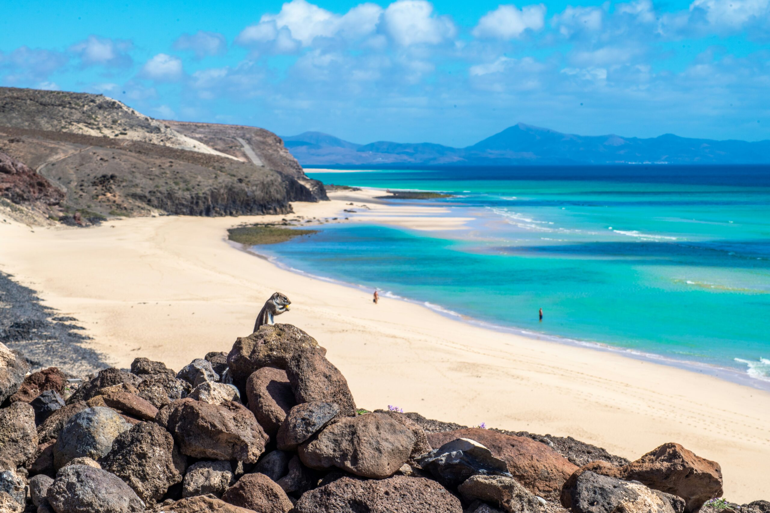 Beach in Fuerteventura with rocks and sand and mountains in background