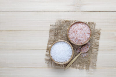 Flatlay pictures of two types of salt, white coarse salt and pink salt