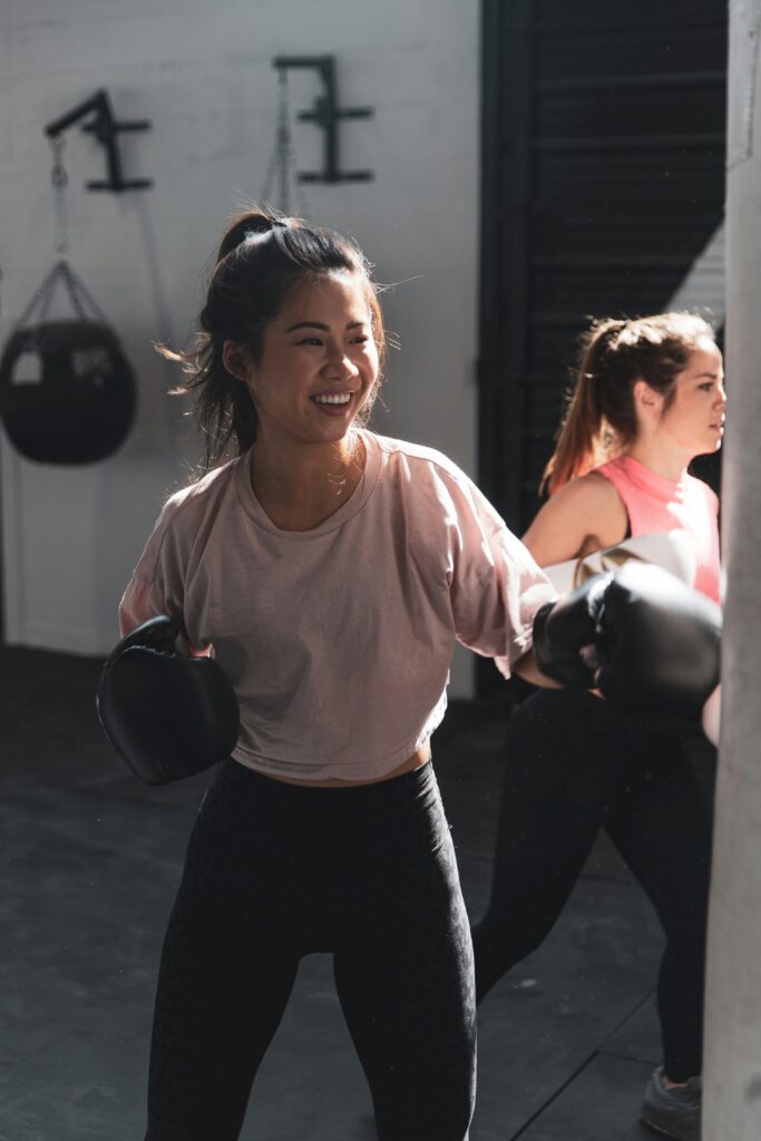 woman in pink t shirt in boxing gym landing a punch