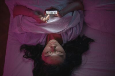 Girl lying on bed in dark using mobile phone