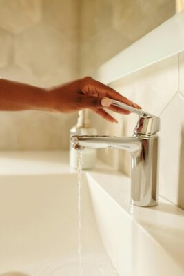 Person turning on running water at sink