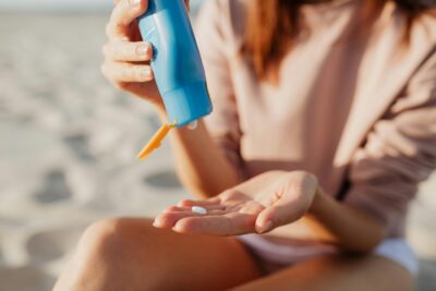 Woman applying SPF from a blue bottle onto hands