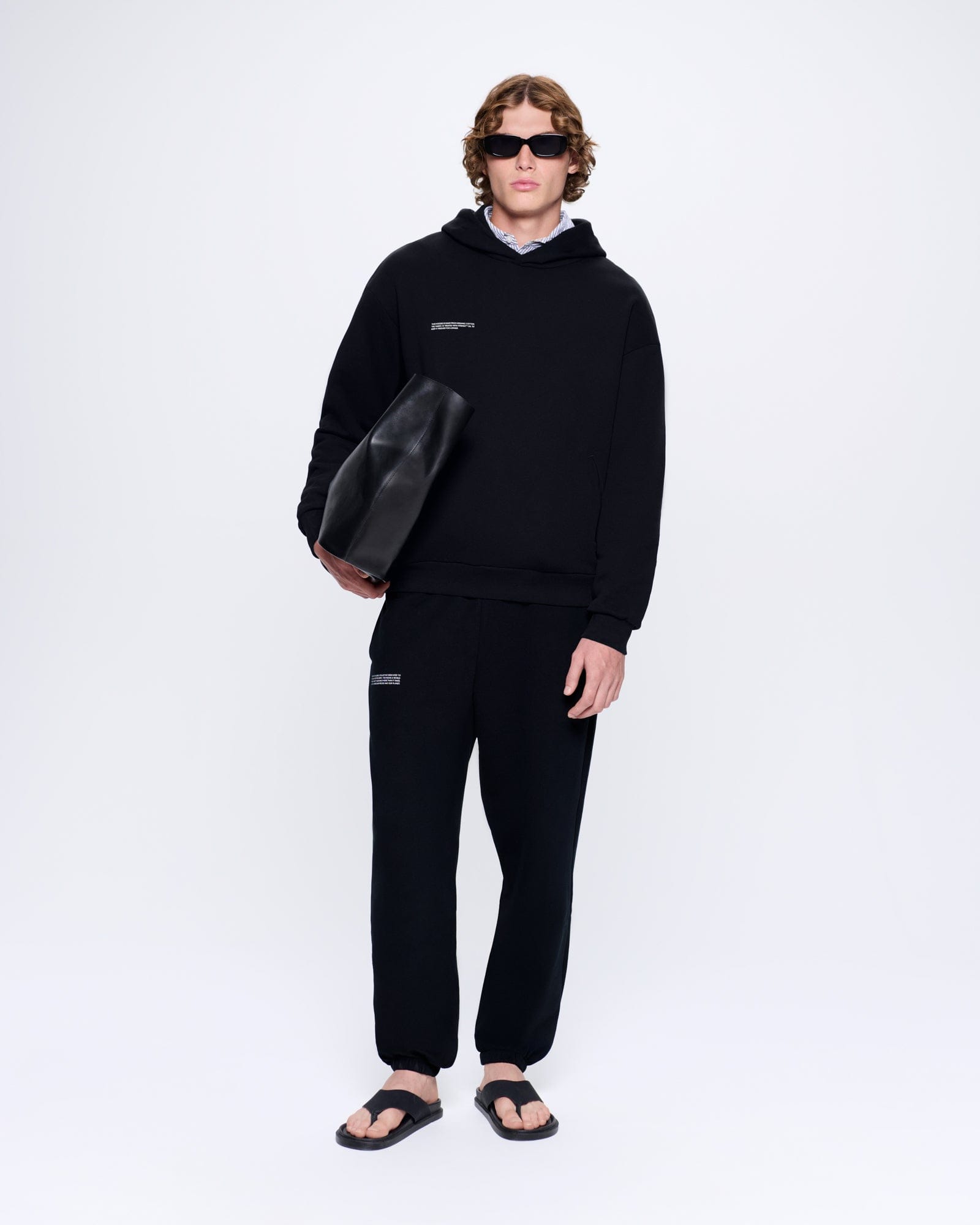 man standing in matching jogger set sunglasses and bag