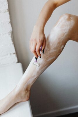 Woman shaving leg with shaving foam spread over skin