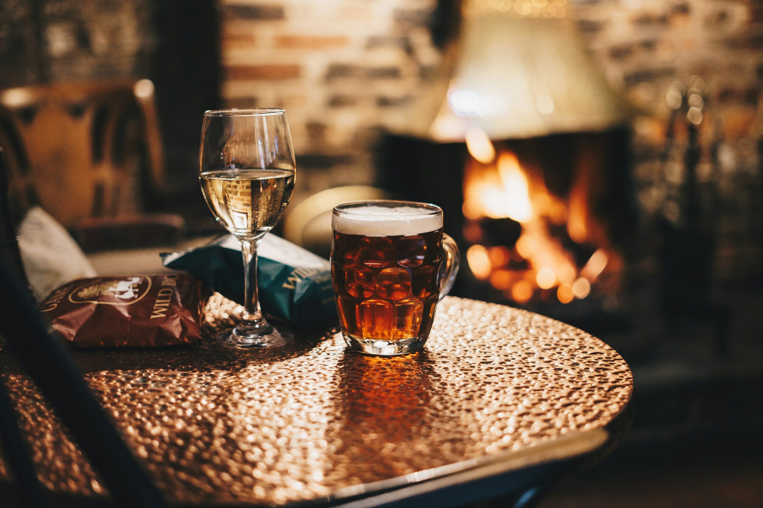 wine glass and beer cup on table by fireside