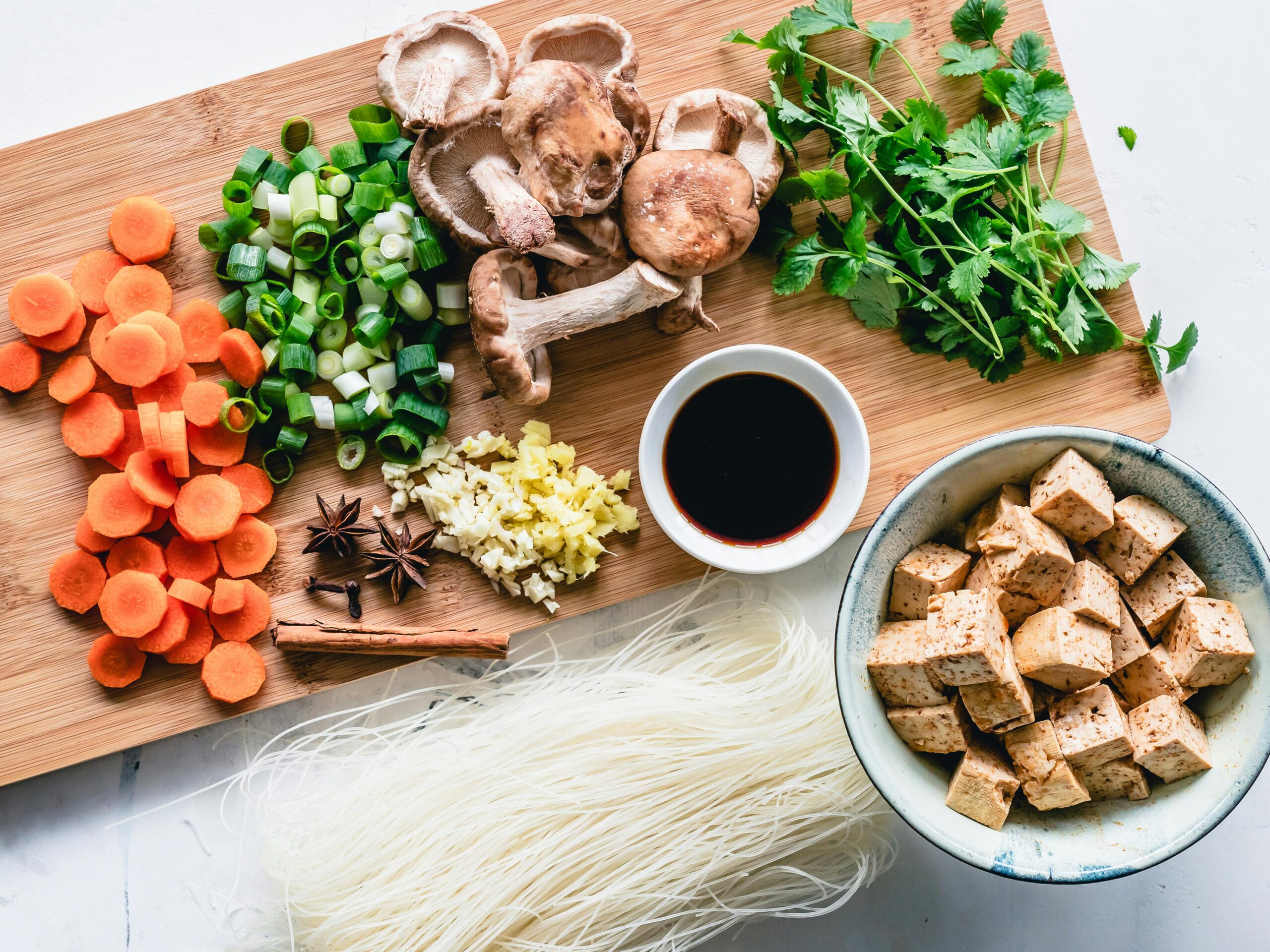 top view of wooden chopping board with vegetables on and a bowl of tofu fake meat substitute