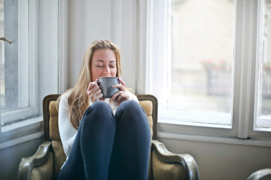 A woman drinks a cup of tea at home