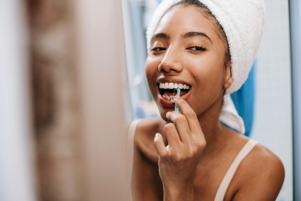 A woman flosses her teeth in the mirror