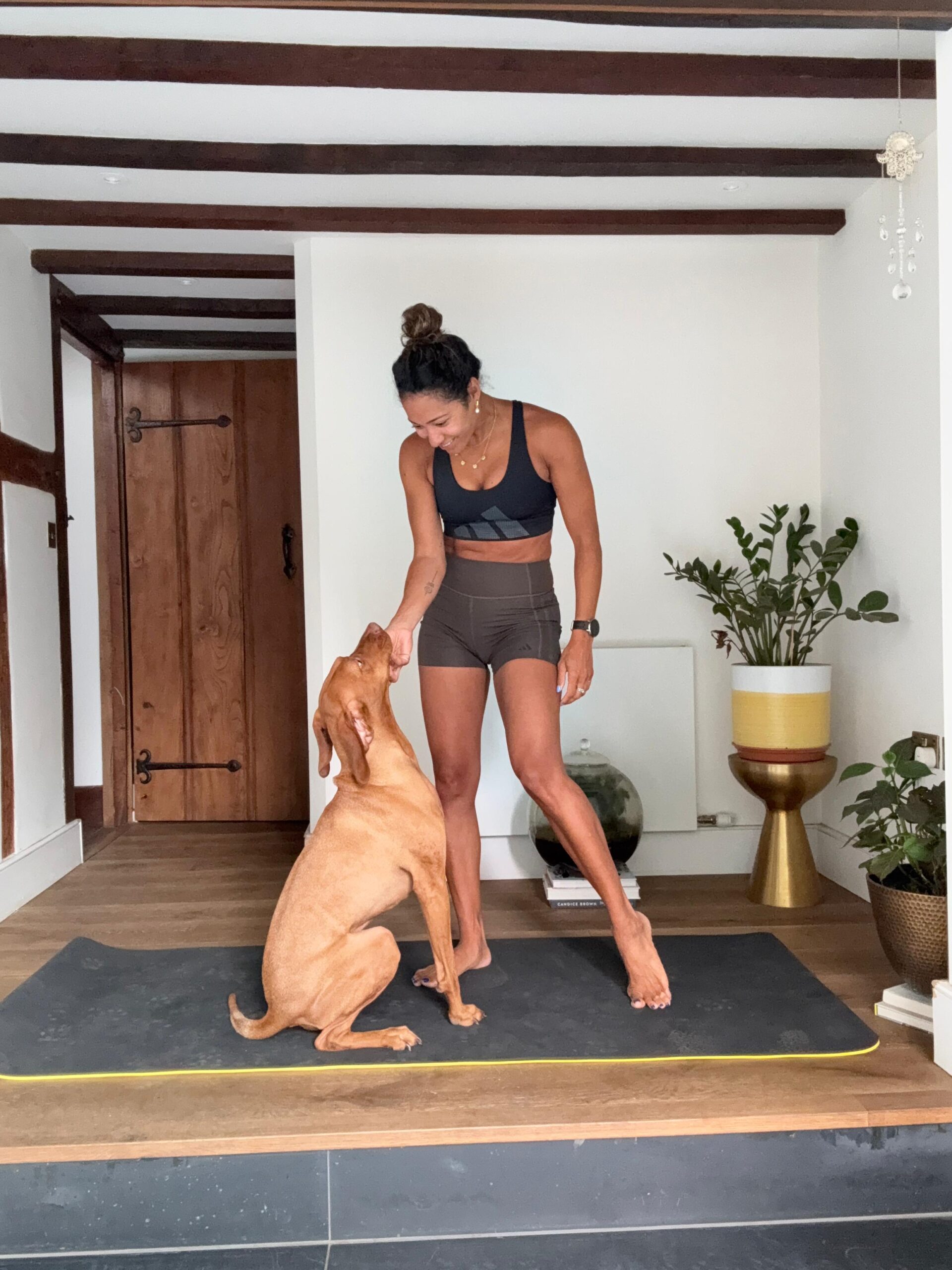 Karen Hauer in her house on a mat working out with her dog