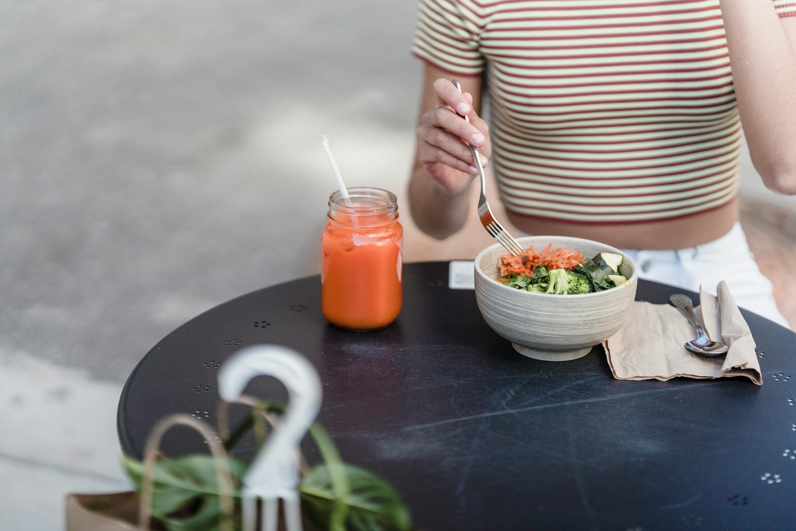 woman sitting at table with a bowl of greenery and a juice