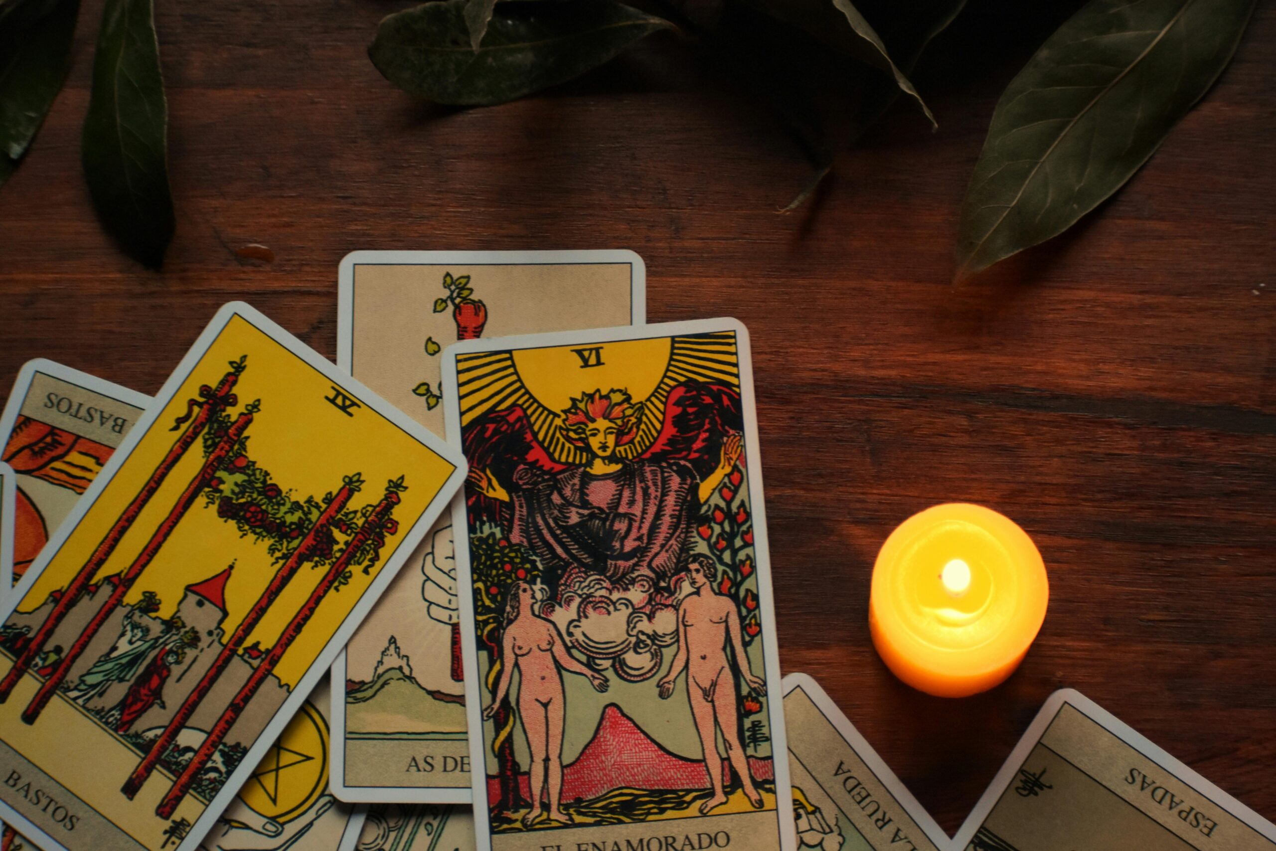 tarot cards on the table with candle lit next to and leaves at top