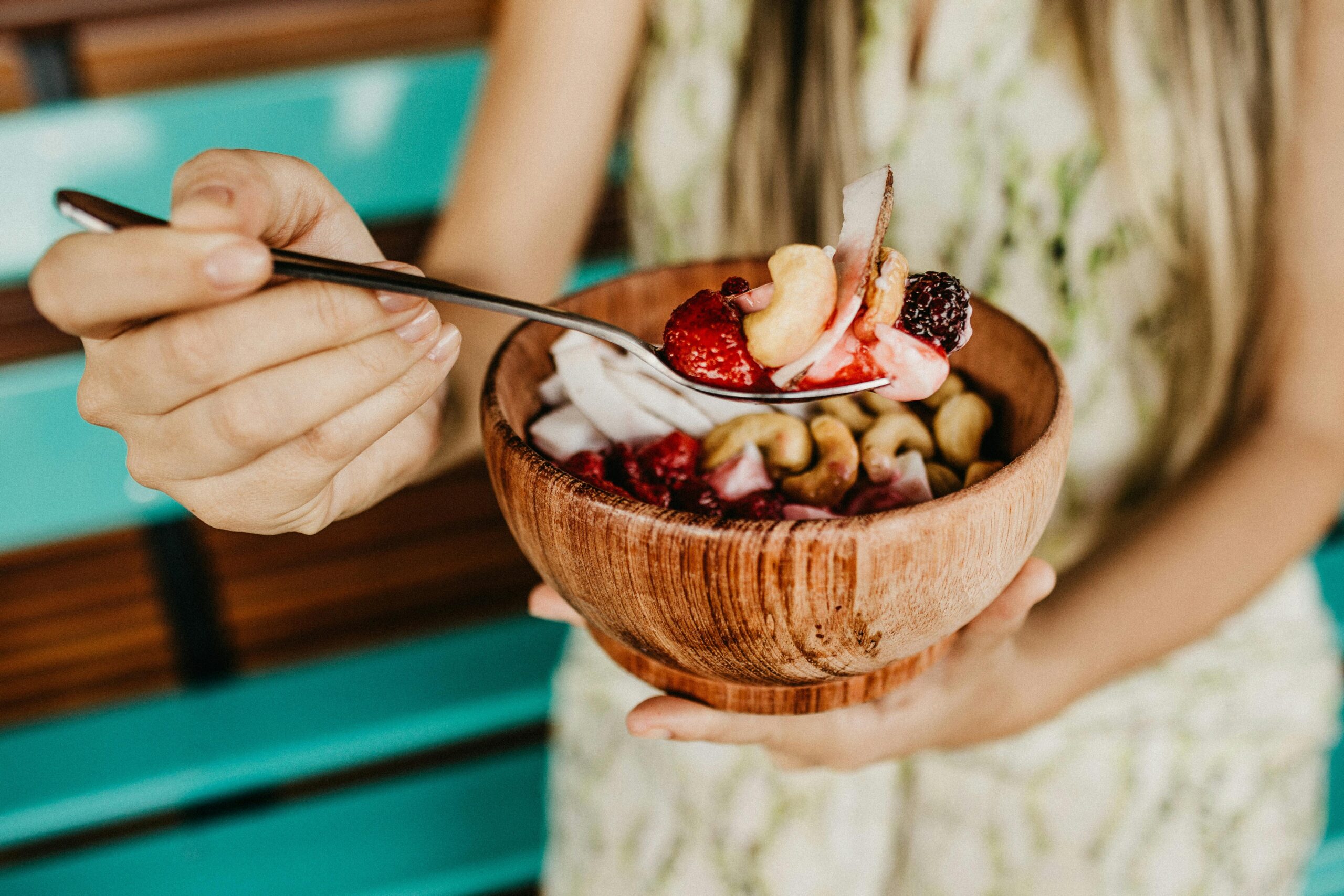 woman holding wooden bowl of foods