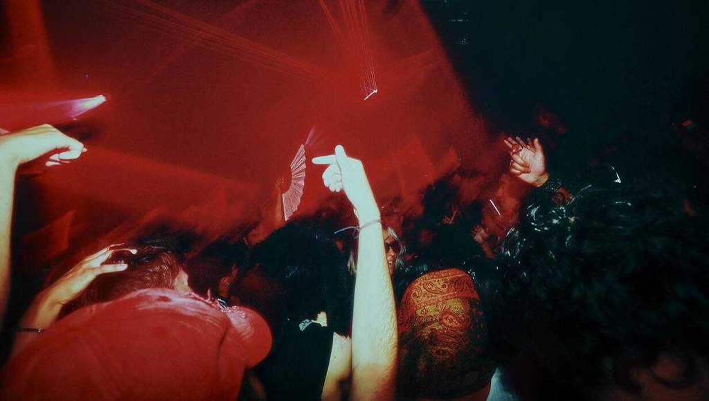 nightclub with red light and hands in the air at the Barbican Centre Anyone Can Dance club night series