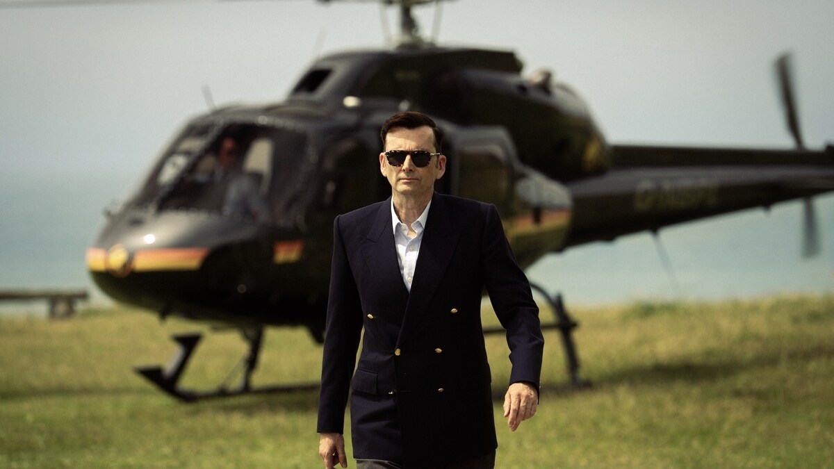 Rivals series 2 Tony Baddingham character walking in front of a helicopter