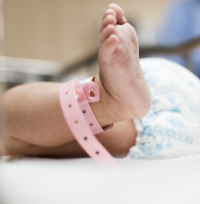 Foot of newborn baby with hospital band on ankle