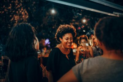 A curly-haired woman laughs at a social event