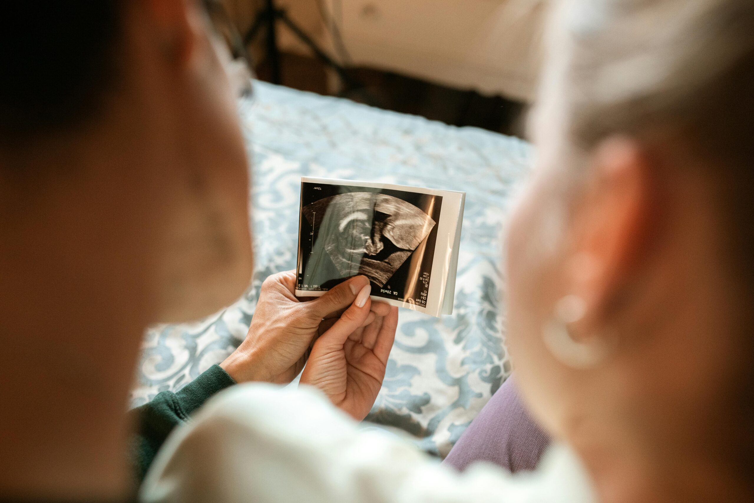 woman holding pregnancy scan to other woman in hand