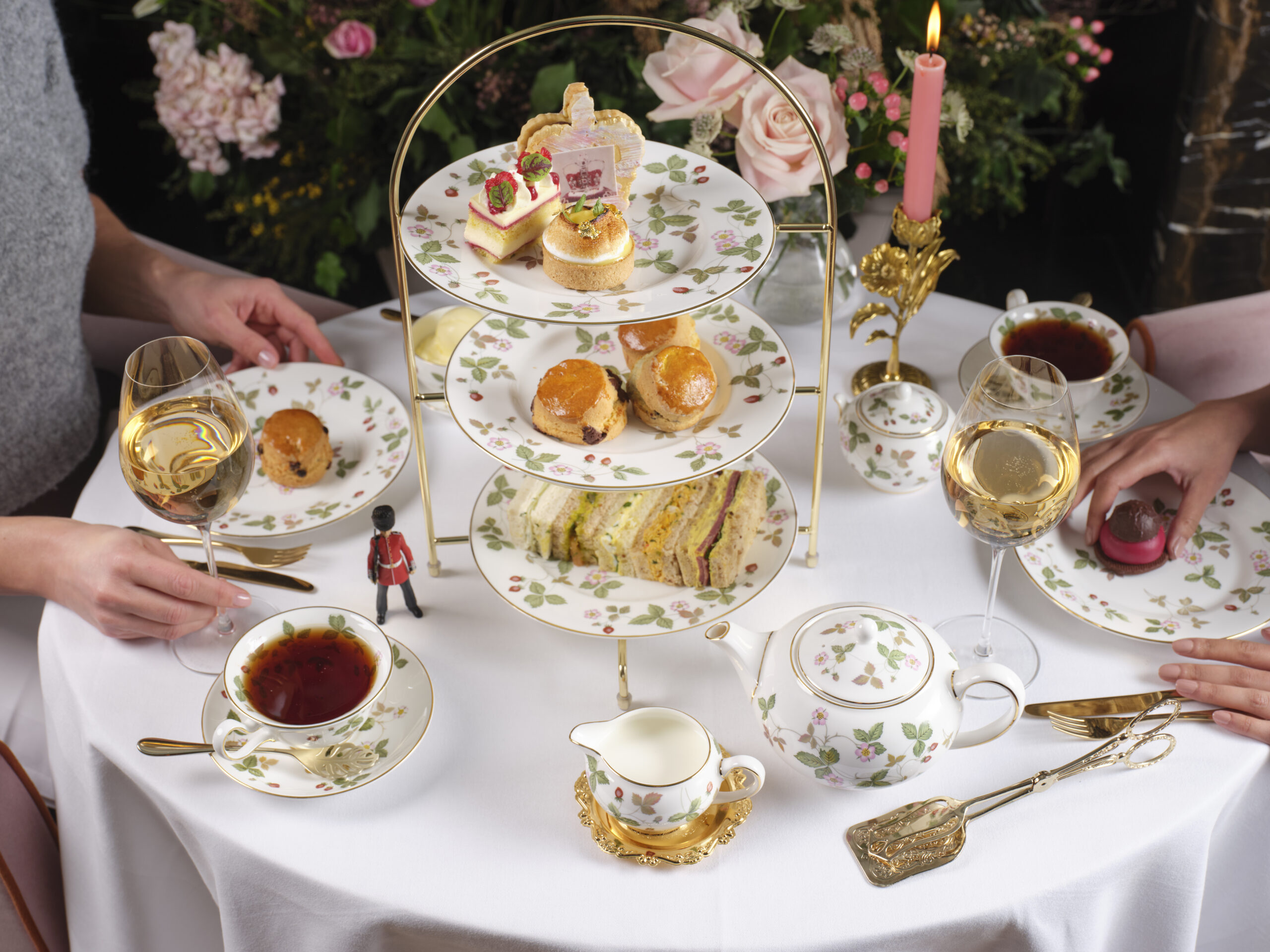 table scape with people enjoying tea and scones on a tiered stand