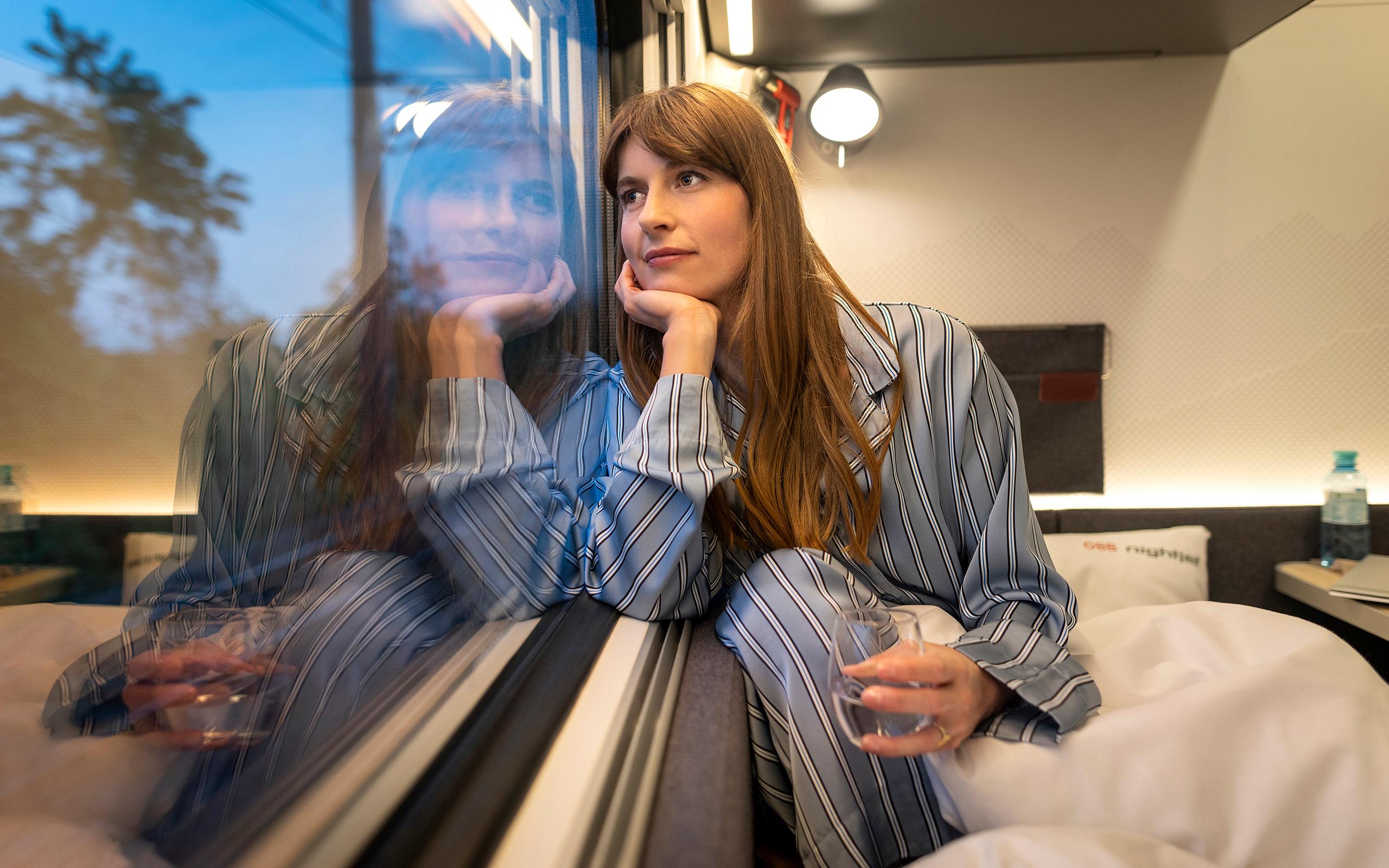 Woman looks out the window of her sleeper train