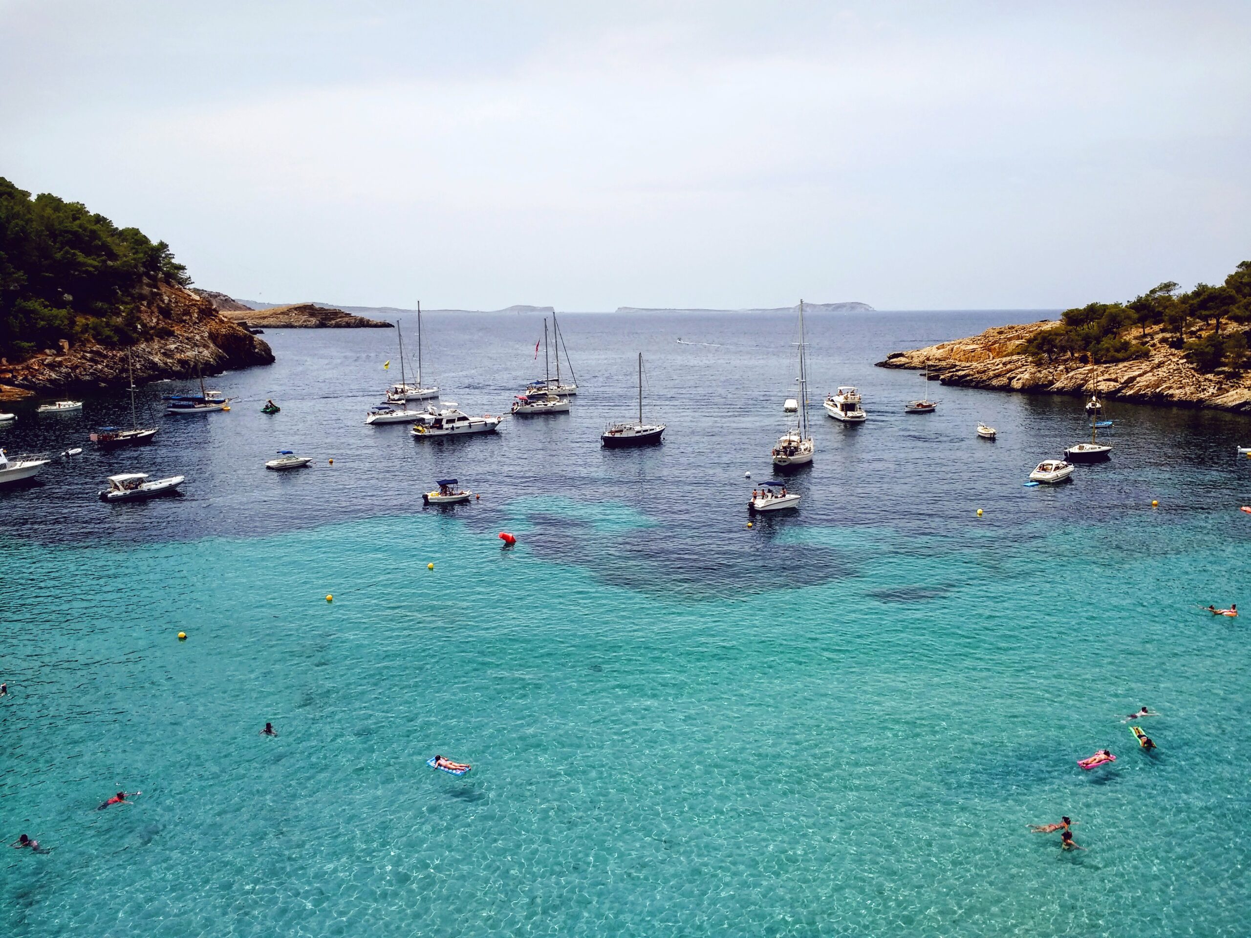 An aerial shot of the beach near Ibiza full of boats and people