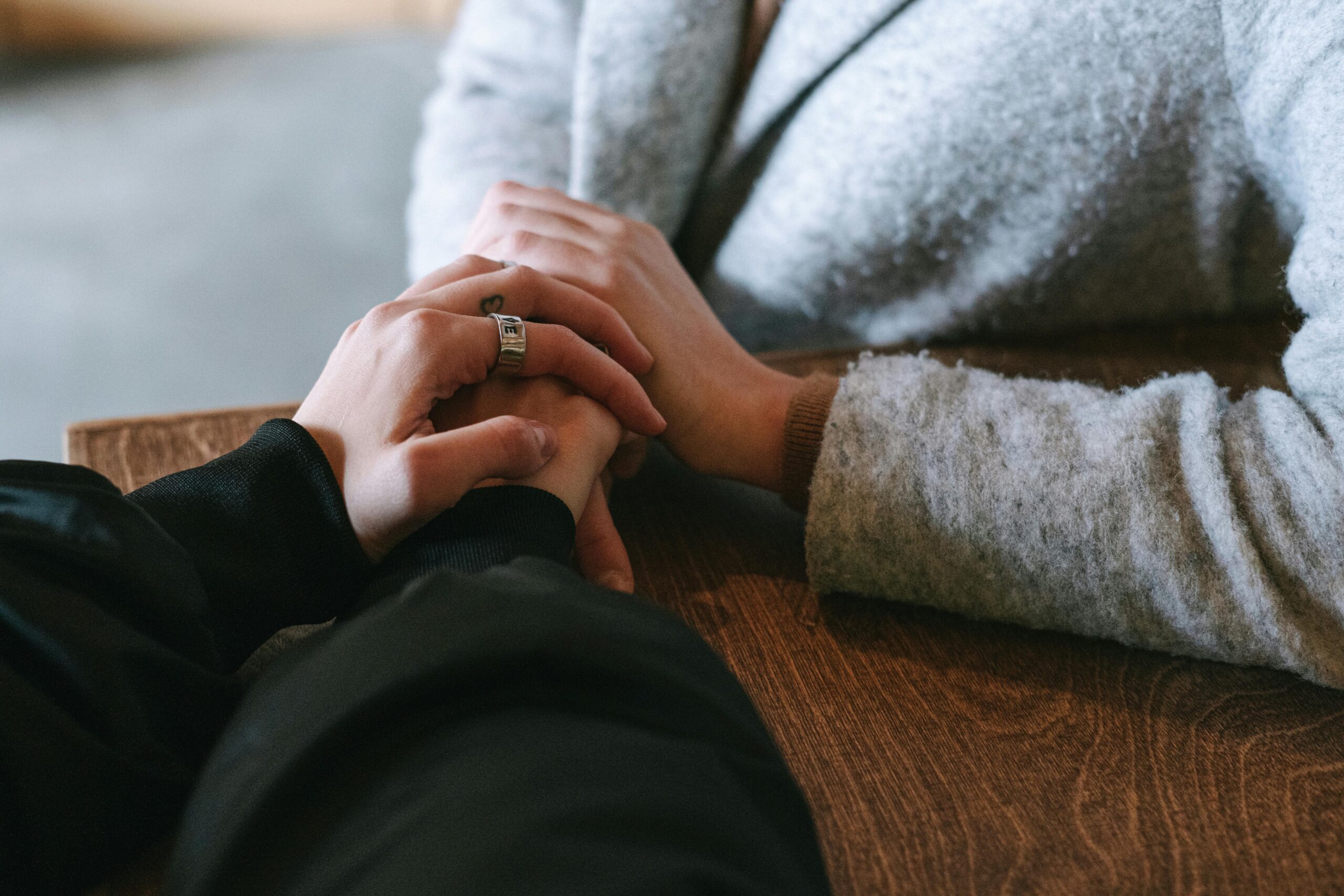 hands of two women clasped over table