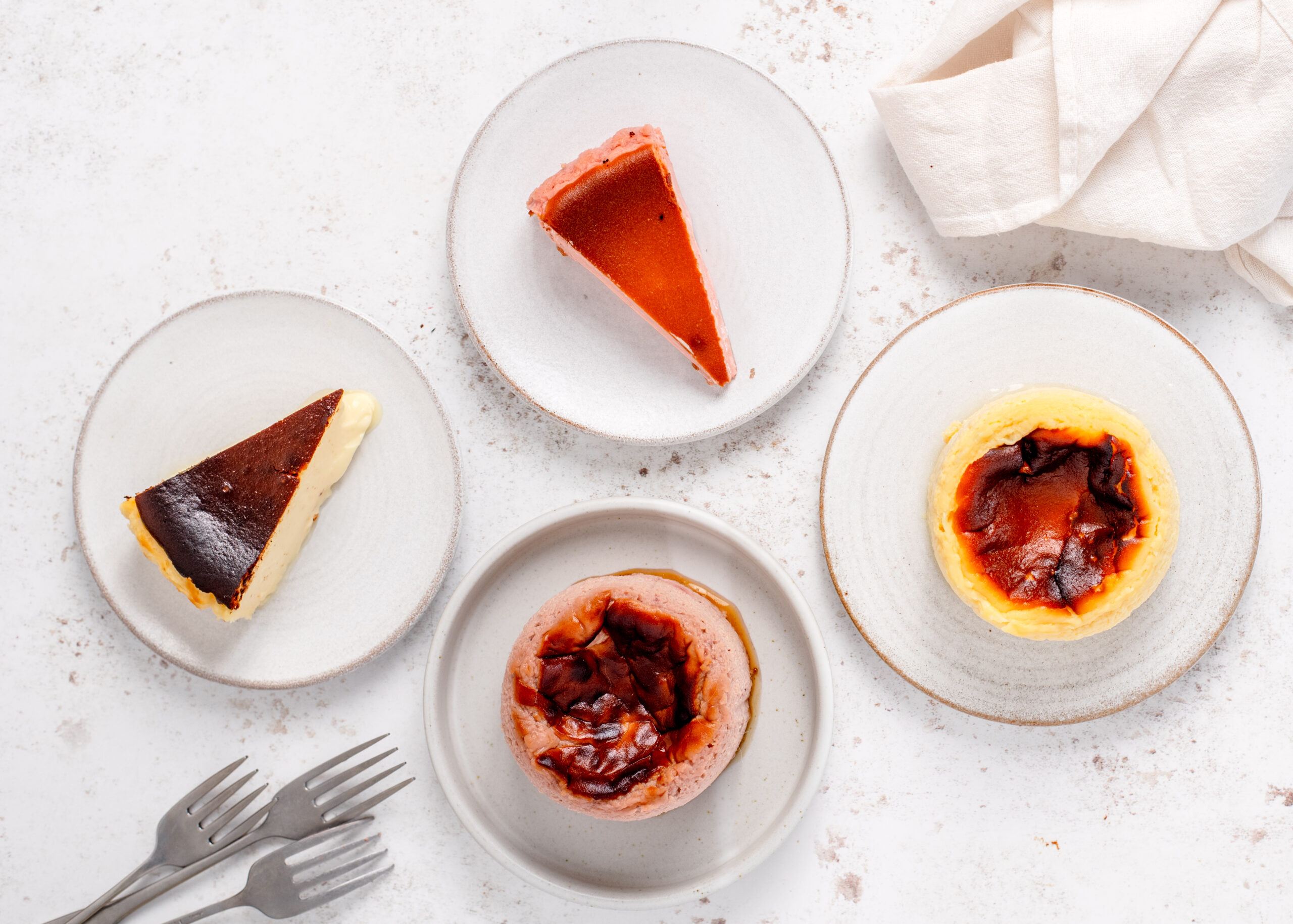 top view of plates with two round cheesecakes and two slices of Basque cheesecake