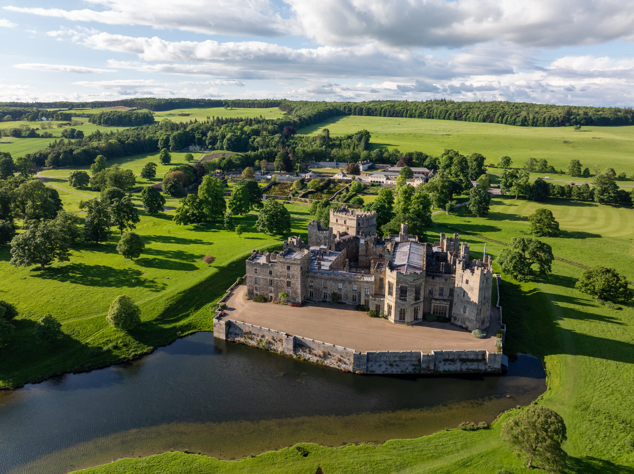 Drone shot of Raby Castle Park and Gardens amid green hills and castle wall