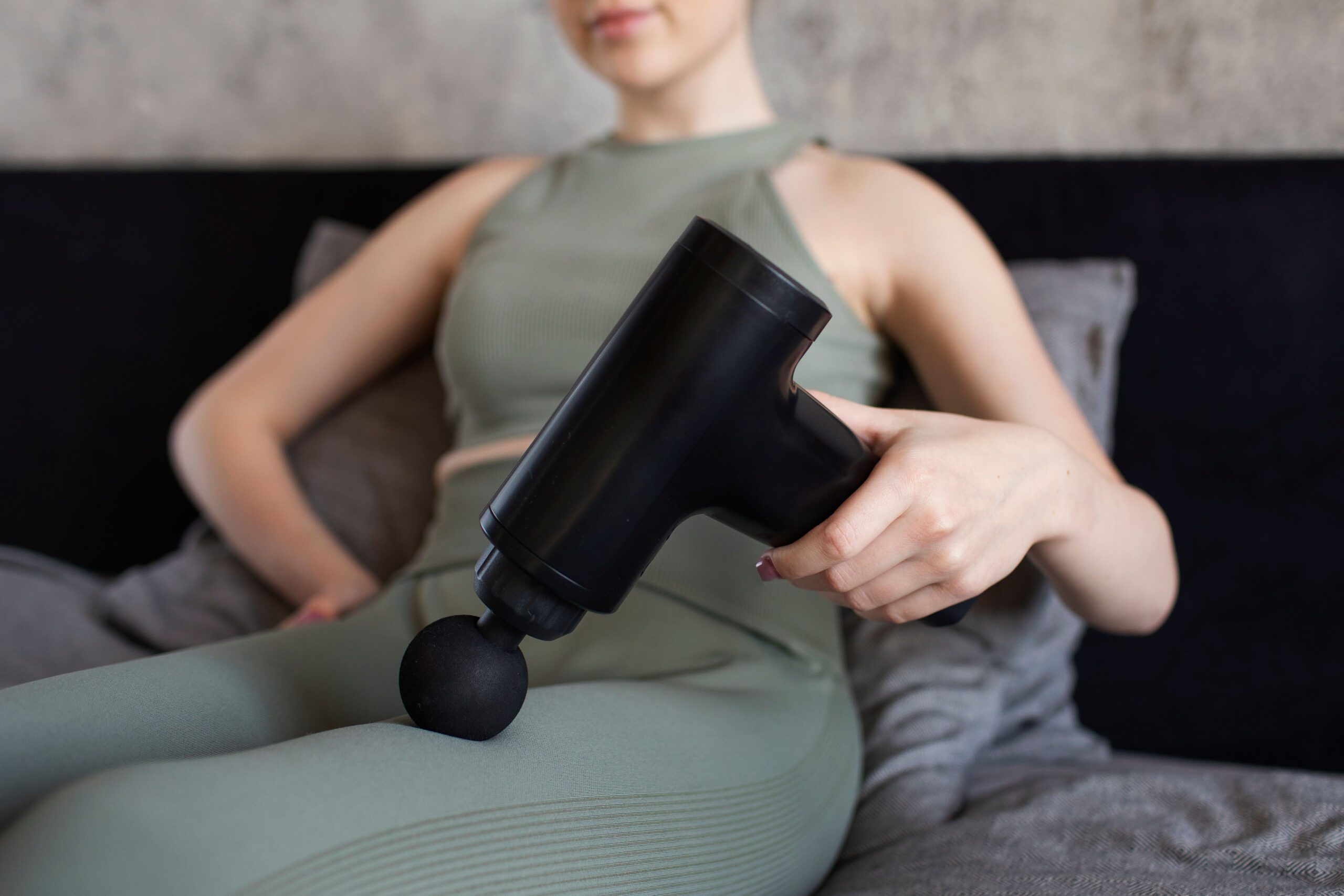 Woman using a massage gun on her legs