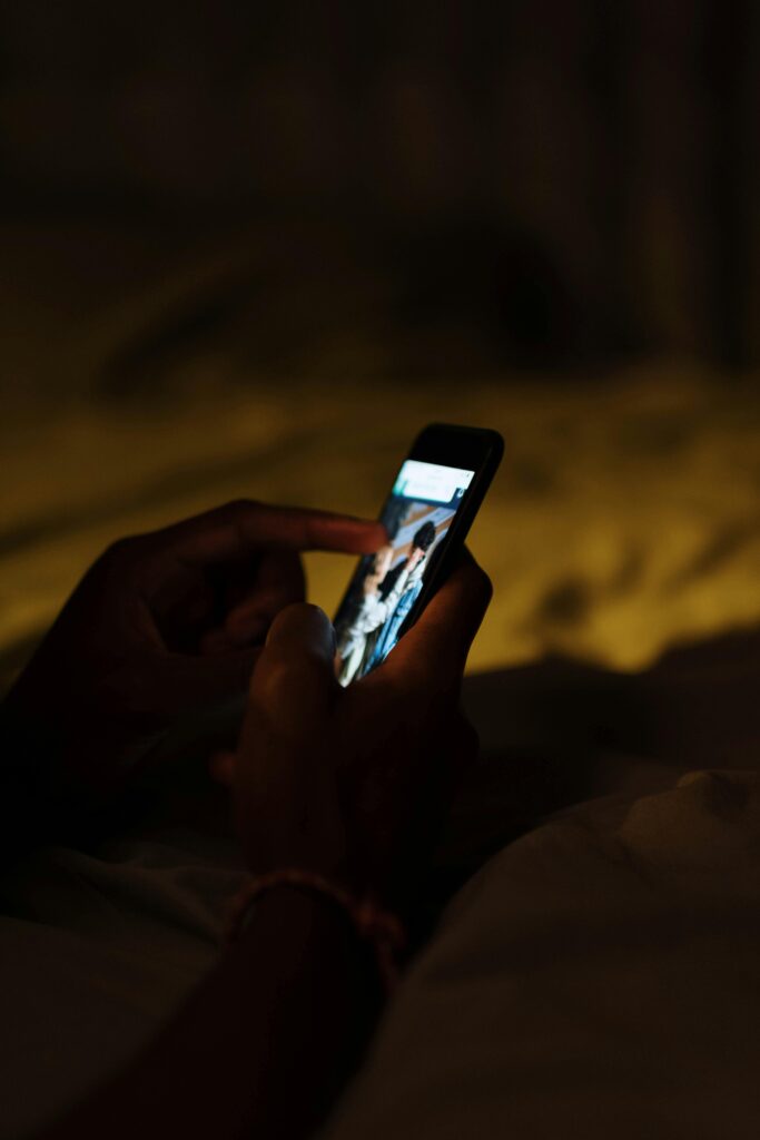 persons hands holding iPhone lit up in the dark