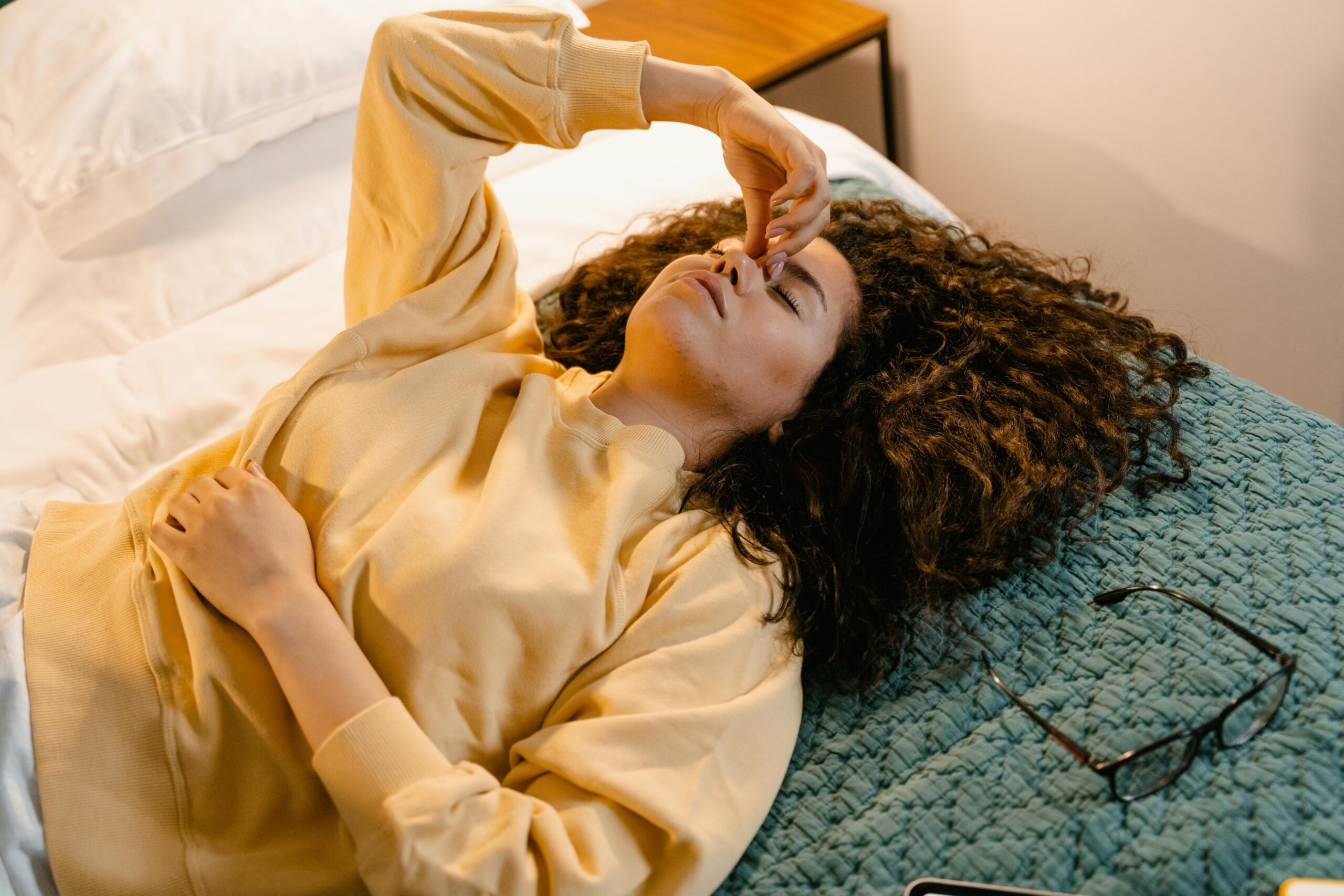 woman lying on bed holding her brow